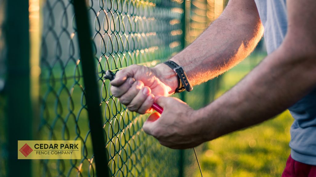 man cutting the wire of chain link fence