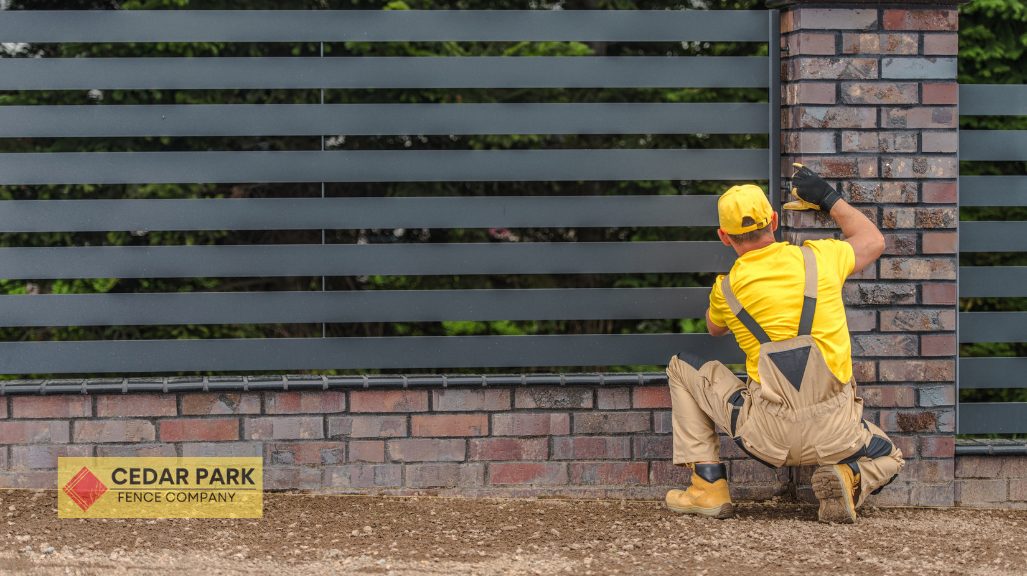 man squatting in front of metal fence